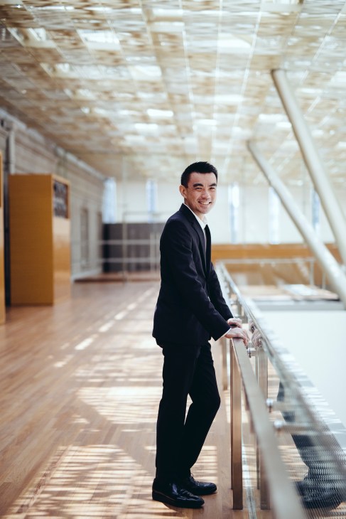 Eugene Tan, National Gallery Singapore director, stands in a bright corridor with geometric skylights and wooden beams overhead.