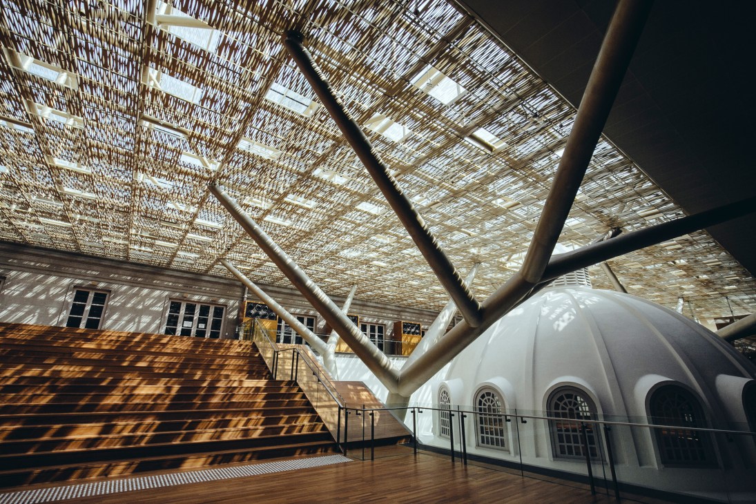 Interior of National Gallery Singapore showing metallic filigree canopy overhead with structural support columns.