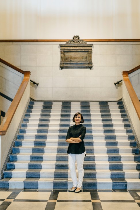 Facilities director Sushma Goh standing on a blue and white checkered staircase in the National Gallery Singapore.