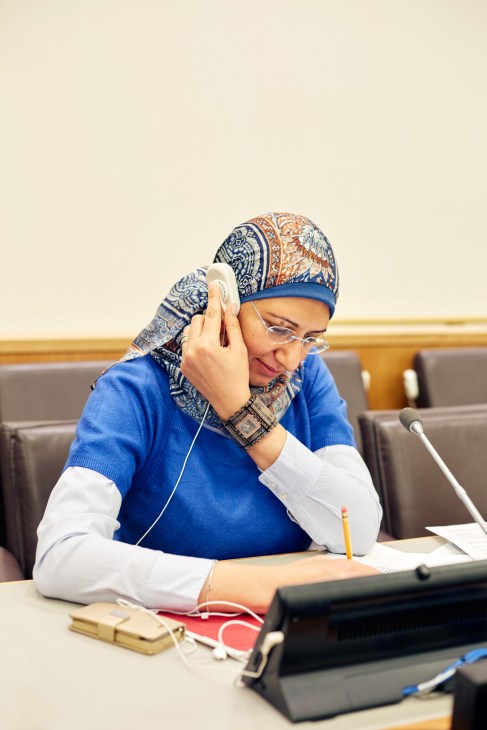 Arabic trainer and interpreter Rama Ahmed adjusting her headphone in a conference room.