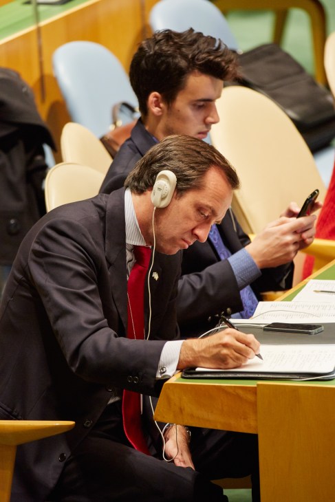Delegate wearing headphones and taking notes at the UN General Assembly Hall.