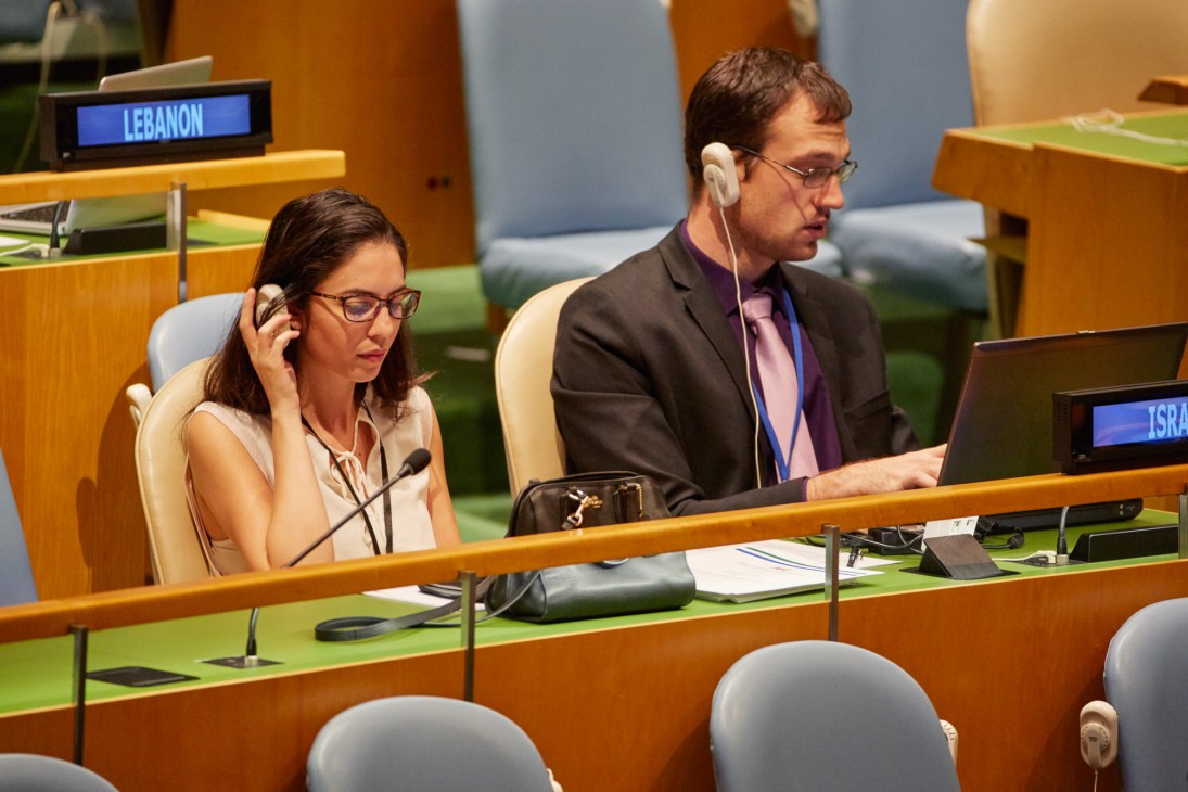 Two delegates wearing headphones listen to interpretation at the UN General Assembly Hall.