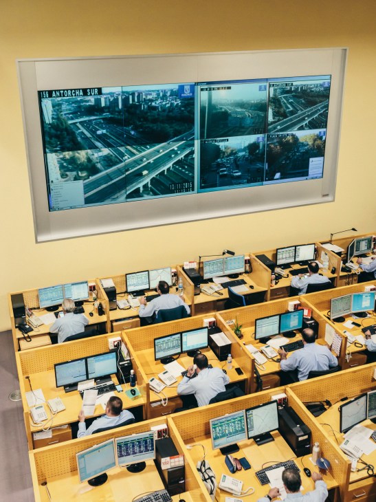 EMT control centre with operators at desks monitoring multiple screens displaying Madrid traffic and transit data.