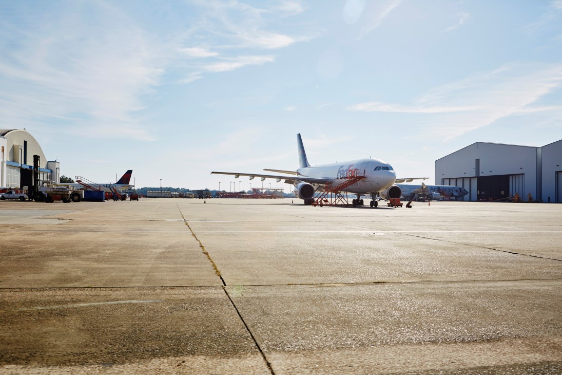 Airbus A321 aircraft parked on tarmac at Mobile assembly facility with support equipment and hangars visible.