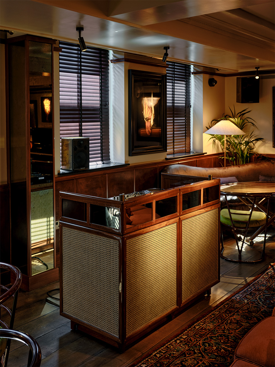 Custom rattan DJ booth with curved design in a warmly lit piano room setting