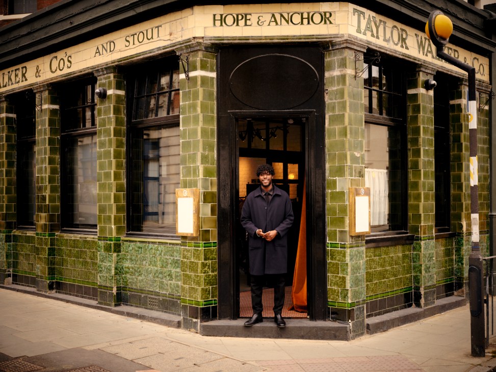 A patron standing in the doors of a 19th century pub with green tiling