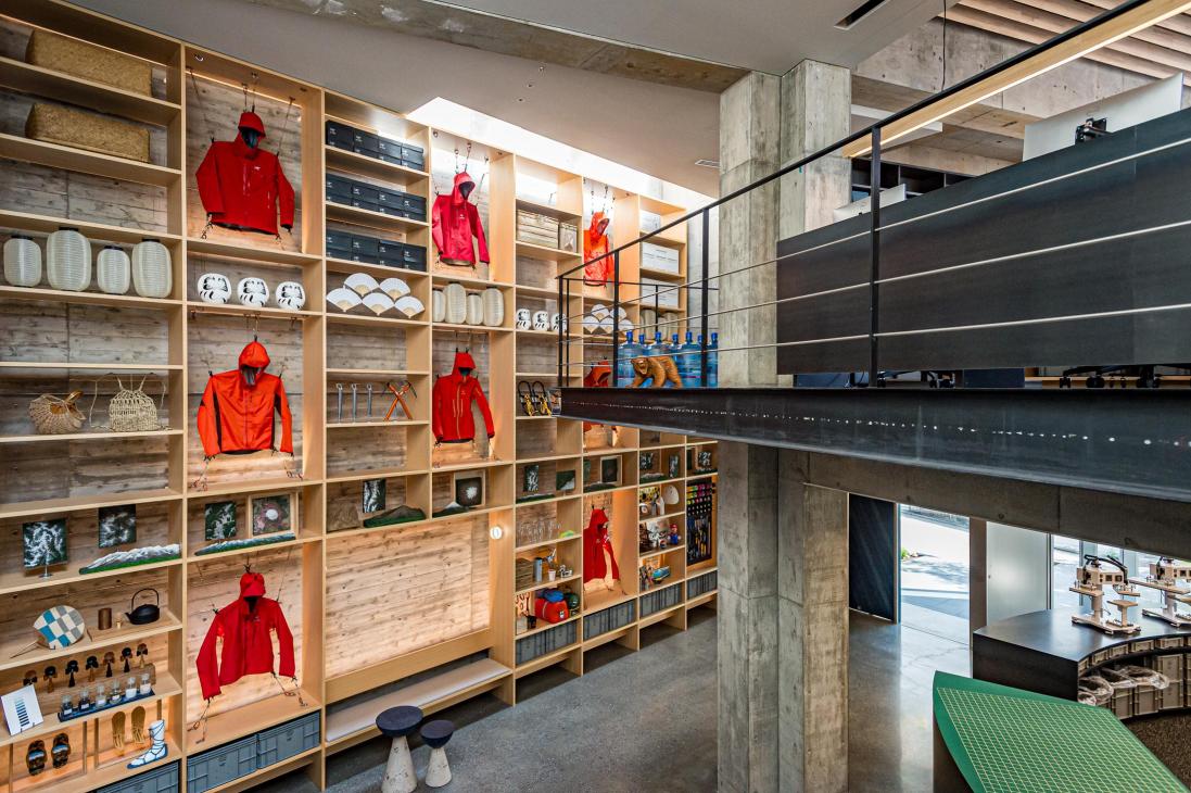 Arc'teryx Tokyo creation centre with wooden shelving displaying red jackets, white dishes, and Japanese design objects.