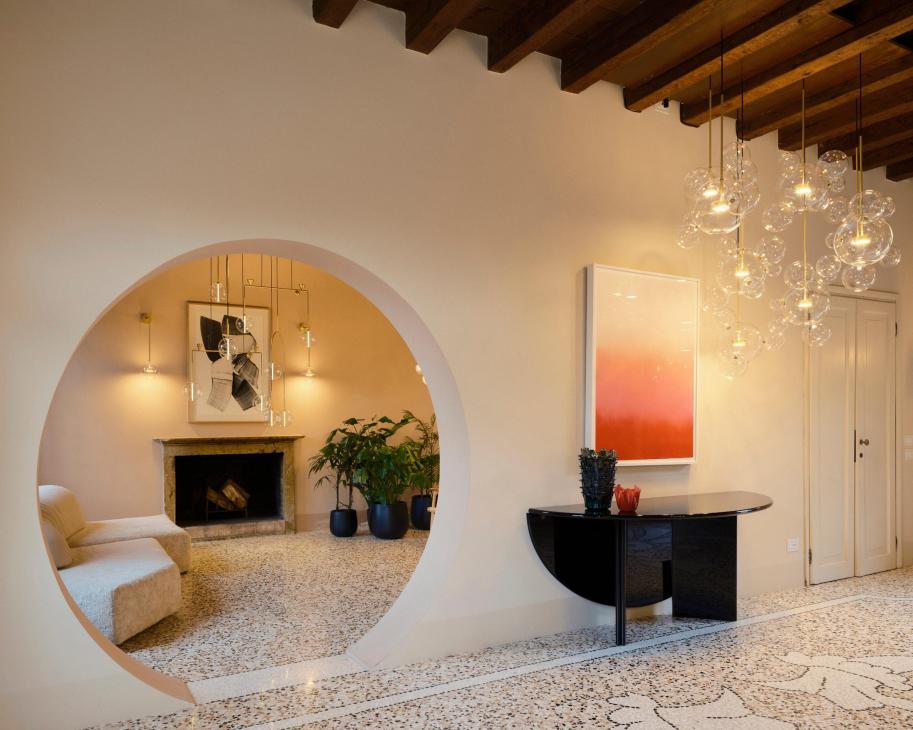 Modern interior room with hanging bubble lights, fireplace, black furniture and colorful artwork.