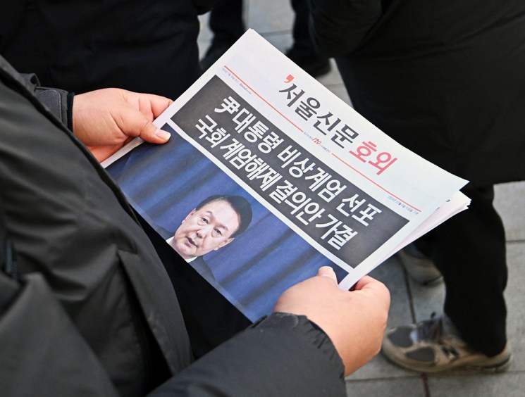 A man reads an extra edition newspaper in downtown Seoul on December 4, 2024, after martial law was lifted. South Korean President Yoon Suk Yeol abandoned a short-lived attempt at martial law on December 4, after lawmakers defied security forces to vote against his declaration and thousands of protesters took to the streets.