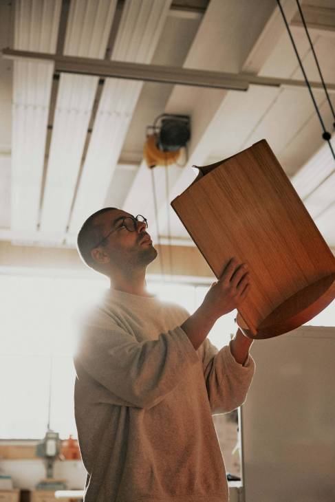 Fabio Rutihauser handling a wooden stool.