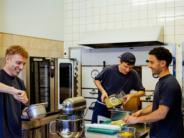 Three males preparing food in a kitchen.