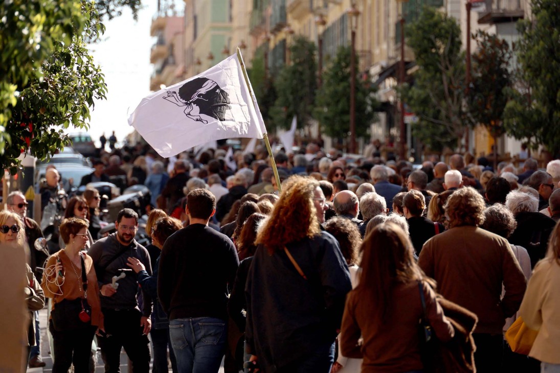 People hold a Corsican flag as they attend a demonstration against mafia in Ajaccio
