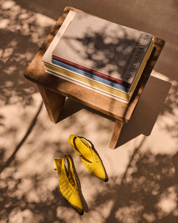 A small coffee table with books atop and a pair of Jacquemus heels