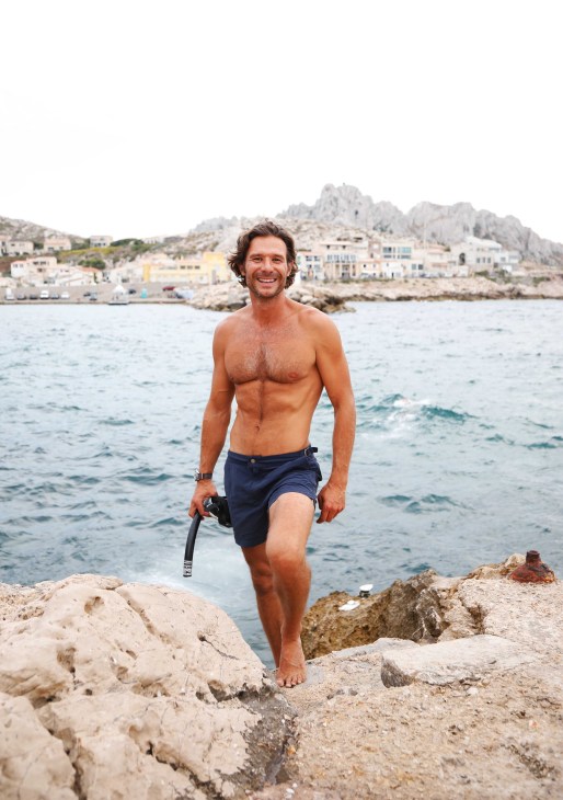 A man in swimshorts at the beach in Les Goudes