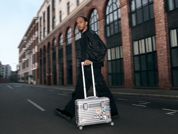 Lewis Hamilton crossing the road with a Rimowa suitcase