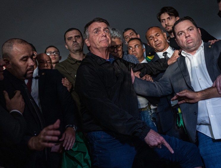 Jair Bolsonaro, Brazil's former president, center, points to his ankle monitor after departing meetings at the National Congress in Brasilia, Brazil, on Monday, July, 2025. US President Donald Trump's tariff threat against Brazil over a legal probe into former President Jair Bolsonaro caught the Supreme Court in Brasilia off guard, with the court in recess during July. Photographer: Arthur Menescal/Bloomberg via Getty Images