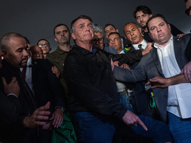 Jair Bolsonaro, Brazil's former president, center, points to his ankle monitor after departing meetings at the National Congress in Brasilia, Brazil, on Monday, July, 2025. US President Donald Trump's tariff threat against Brazil over a legal probe into former President Jair Bolsonaro caught the Supreme Court in Brasilia off guard, with the court in recess during July. Photographer: Arthur Menescal/Bloomberg via Getty Images