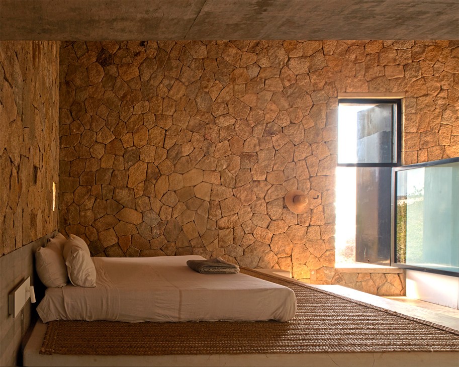A double-height bedroom is clad in stones, mirroring Casa Cometa’s exterior