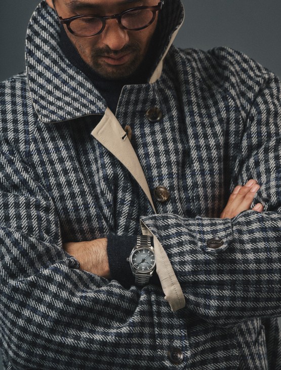 Male model in coat by Miu Miu, high-neck
jumper by Kaptain Sunshine, glasses
by Lindberg, seamaster railmaster
watch by Omega