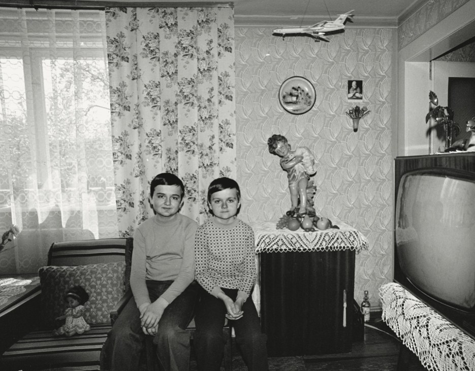 Black and white photograph of two young
boys sat together in a living room.