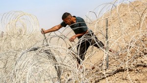 A man attempts to remove parts of the barbed-wire fence at the so-called "Netzarim corridor" near Nuseirat in the central Gaza Strip