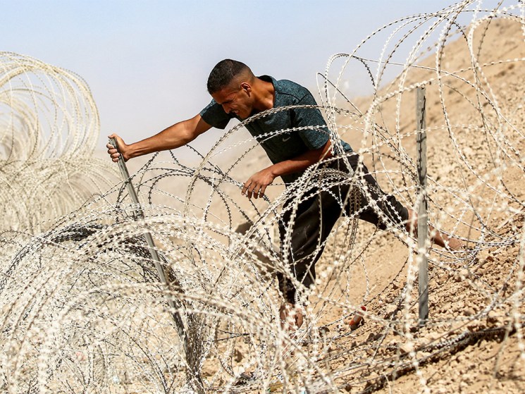 A man attempts to remove parts of the barbed-wire fence at the so-called "Netzarim corridor" near Nuseirat in the central Gaza Strip