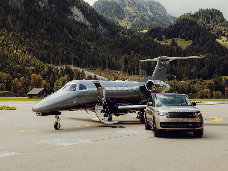 A Range Rover and jet parked on a runway