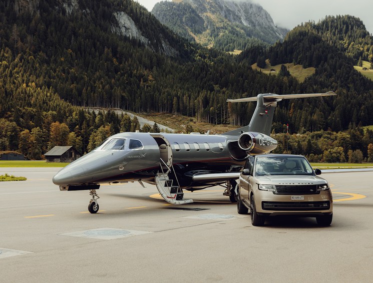 A Range Rover and jet parked on a runway
