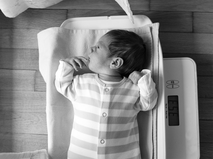 Newborn baby lies on a weighing scale