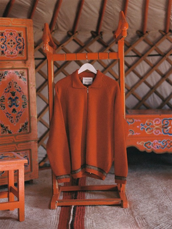 Jumper designed by A Kind of Guise hangs on a rail in a Mongolian yurt