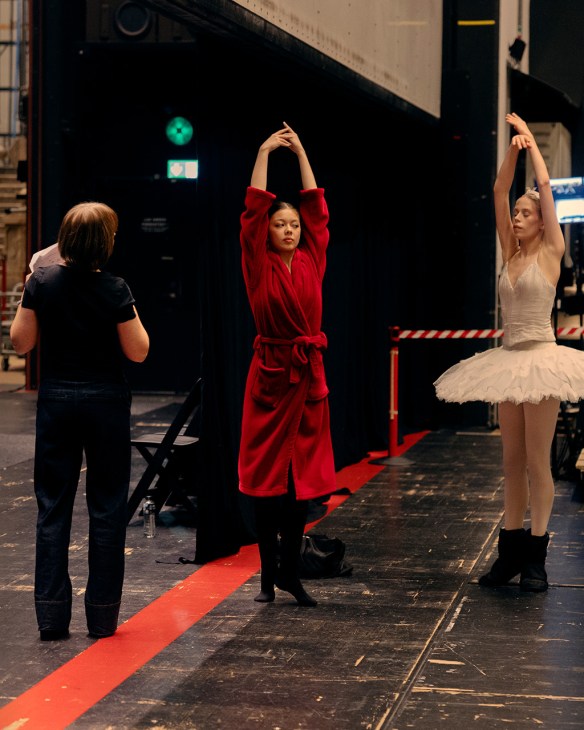 Two ballet dancers in costume stretch backstage