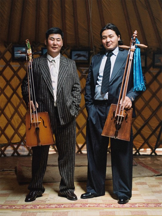 Two men in suits holding traditional Mongolian instruments