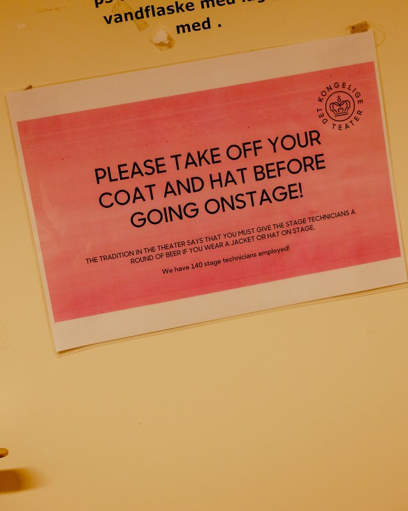 A sign reads 'please take off your coat and hat before going onstage'