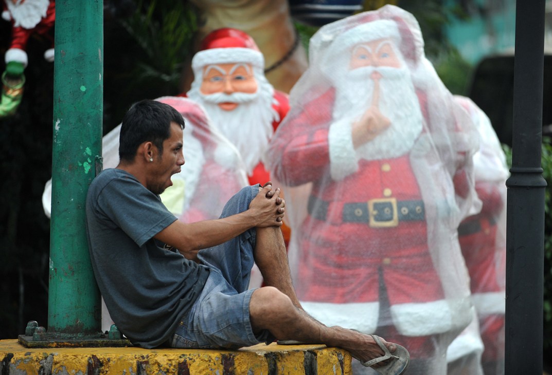 A man sits by a Christmas display near a store in Manila on December 3, 2010. A senior statesman of the Philippines' dominant Catholic church has accused Santa Claus of stealing the true spirit of Christmas, which he said is deteriorating into a shopping frenzy. AFP PHOTO/NOEL CELIS (Photo credit should read NOEL CELIS/AFP via Getty Images)