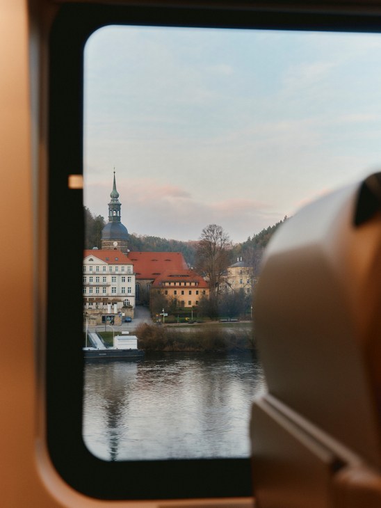 View of a river and houses from the window of the Ceske Drahy Comfortjet