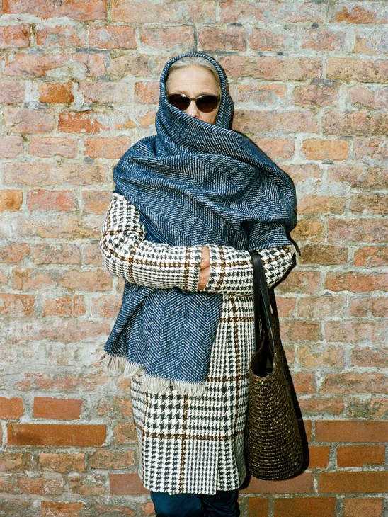 Woman Bundled up in tweed coat and oversized scarf with sunglasses