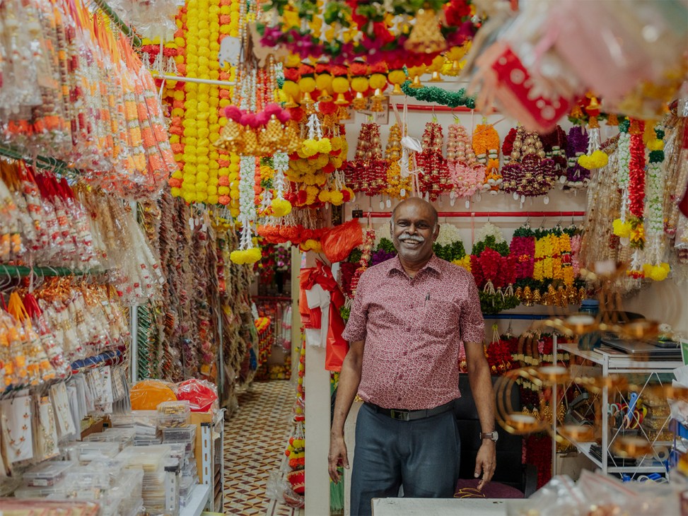 Owner of Anushia Flower Shop, R Jayaselvam, stands in front of his store