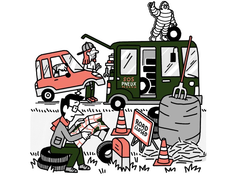 Andrew Tuck reading a map while his car gets new tyres