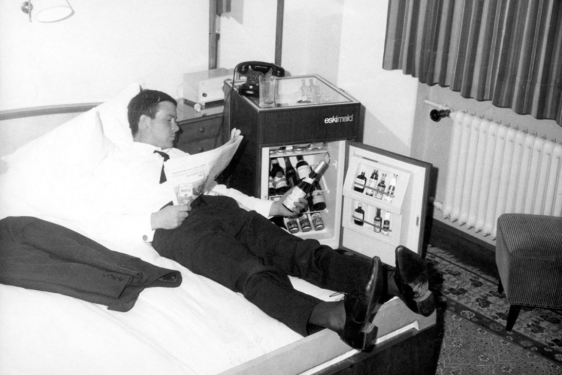 Man enjoys a bottle from the fridge of his hotel mini bar 