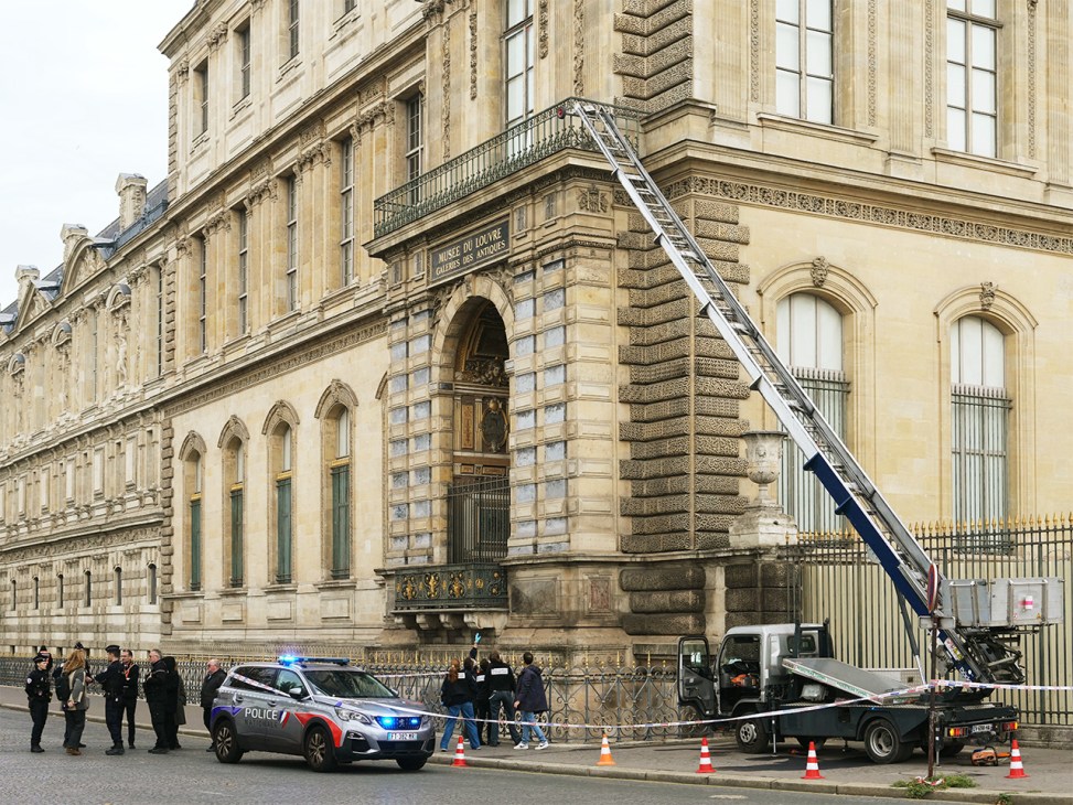 Police officers next to a furniture elevator used by thieves to enter the Louvre