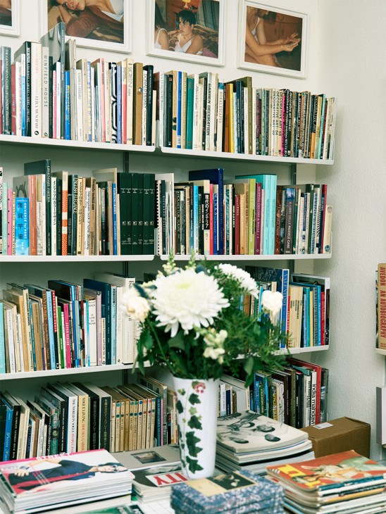 Shelves filled with books and magazines at Idea bookshop in London, with white flowers in a vase on the desk below.