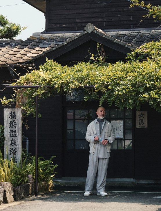 Chef Shinichiro Harakawa stands outside a traditional Japanese building wearing a cardigan and rollneck jumper by Brunello Cucinelli.