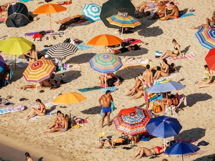 Beachgoers under umbrellas on the sand