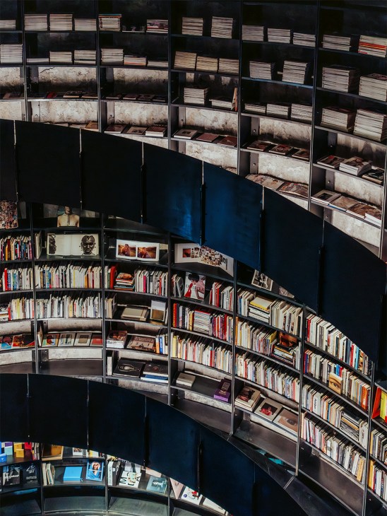 Cylindrical silo-shaped library interior with floor-to-ceiling shelves holding books and magazines in curved rows.