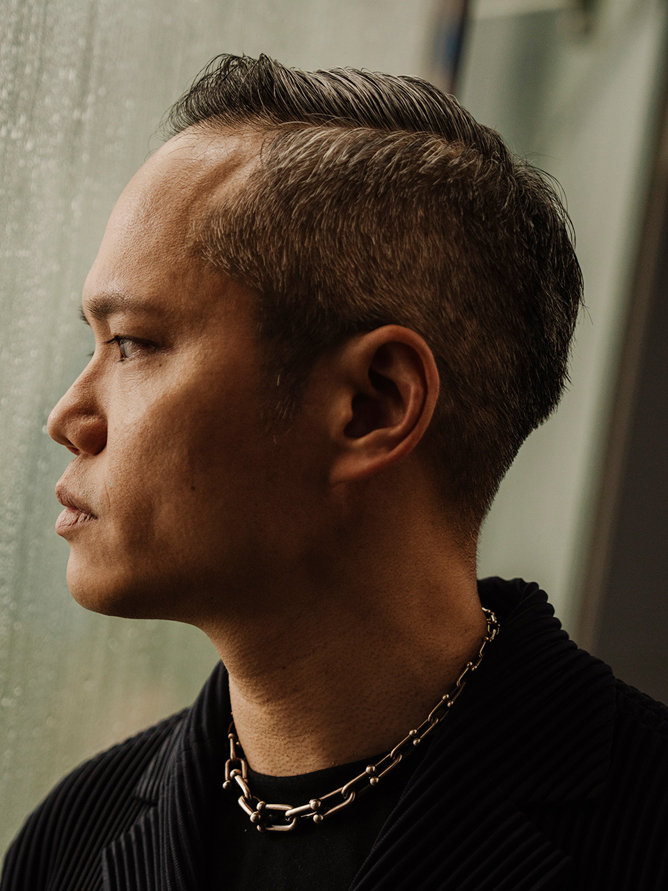 Ruben Chong, founder of Calvary Carpentry, in profile wearing a black shirt and chain necklace.