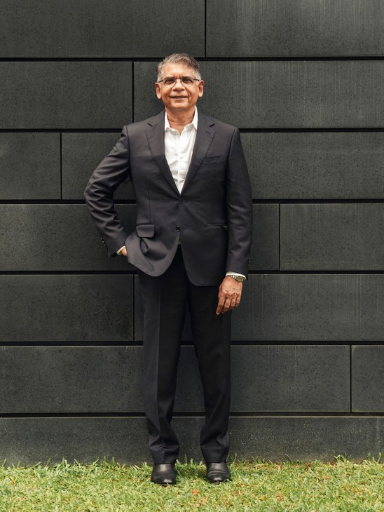 Venka Purushothaman, president of Lasalle College of the Arts, standing in front of a textured dark wall.