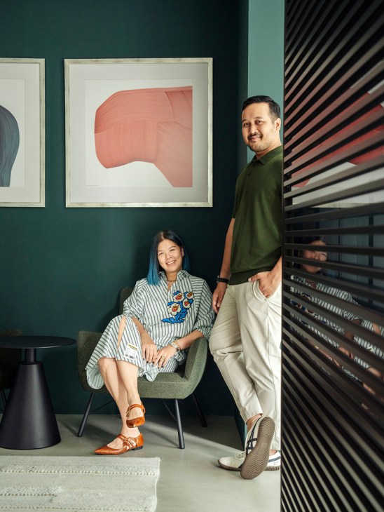 Ruiyin Lin and Afzal Imram, founders of State Property, pose together in a gallery space with framed artwork on teal walls.