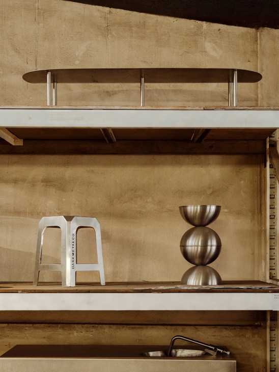 Shelving display featuring Baremetalco metalware including stacked brass bowls and a white stool.