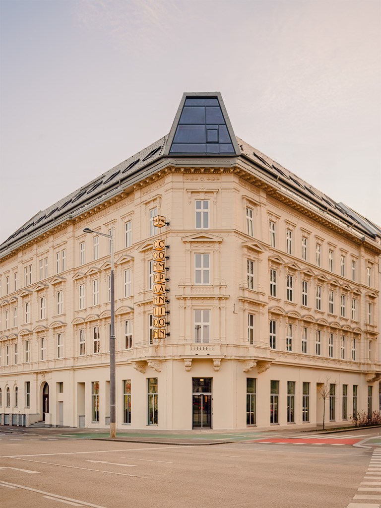 Pale cream-colored Wilhelminian corner building with ornate classical details and modern solar panel roof extension.