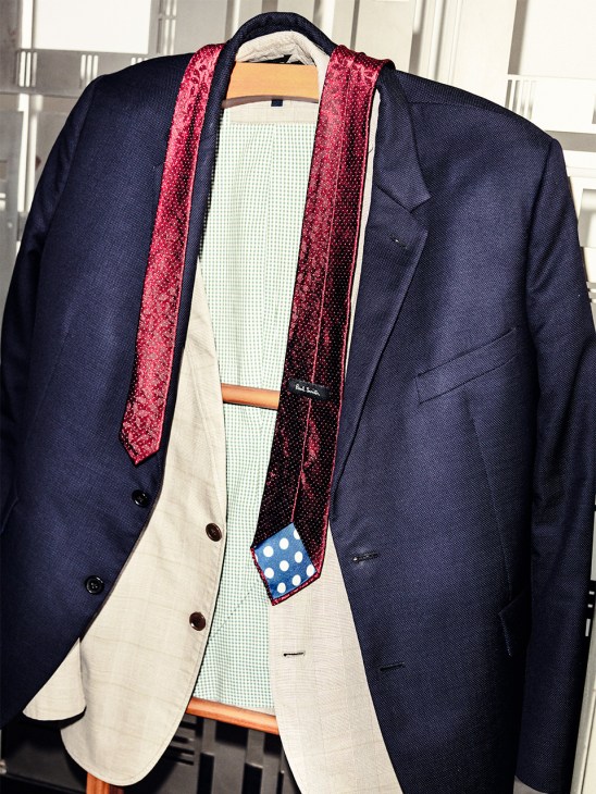 Navy blazer with cream shirt and red patterned tie on wooden hanger